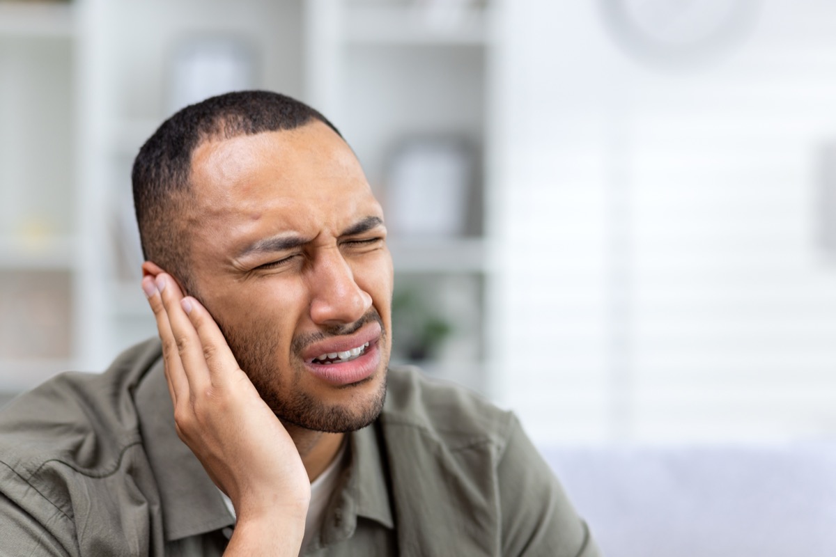 Person holding their ear in pain during a telehealth visit